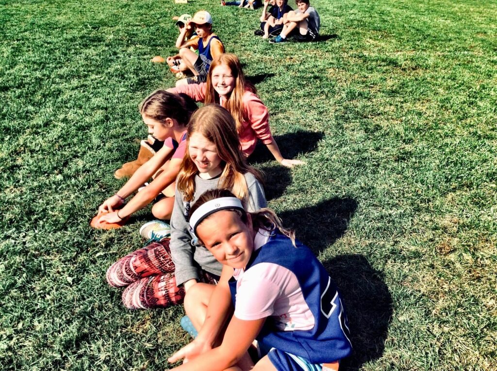 Group of children sitting in a grassy park, enjoying a sunny summer day together.