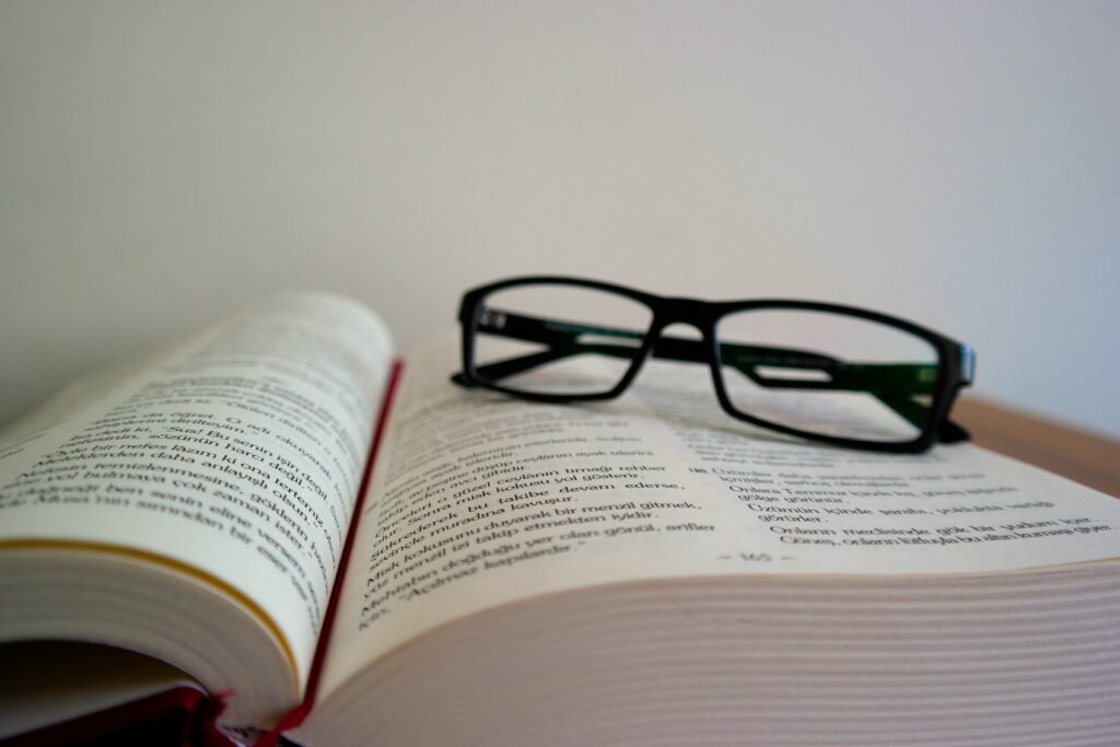 An open book with eyeglasses resting on top, symbolizing learning and education.